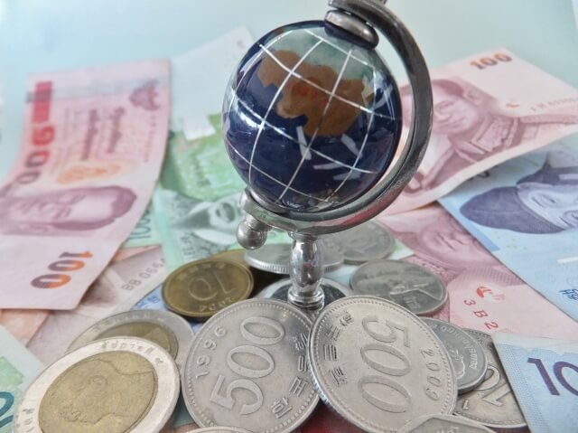 世界の通貨の上に地球儀がある